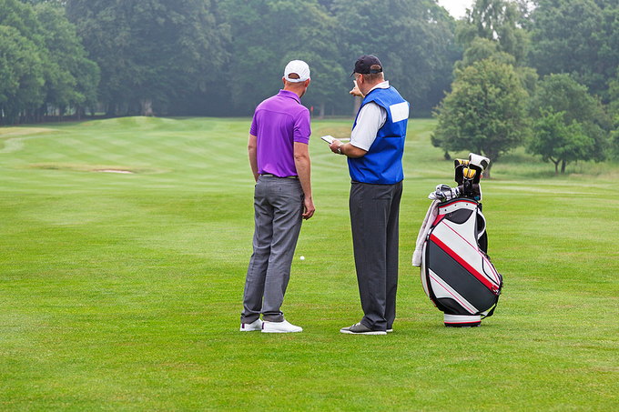 Golfer and Caddy Discussing Shot